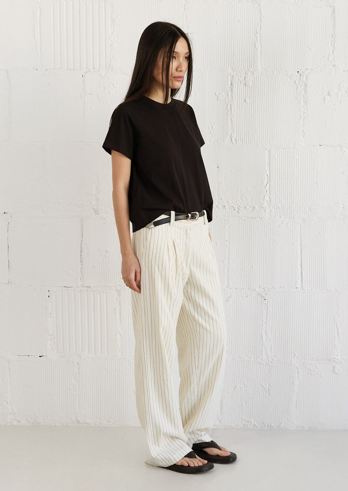 A woman wearing a black t-shirt and white pants.