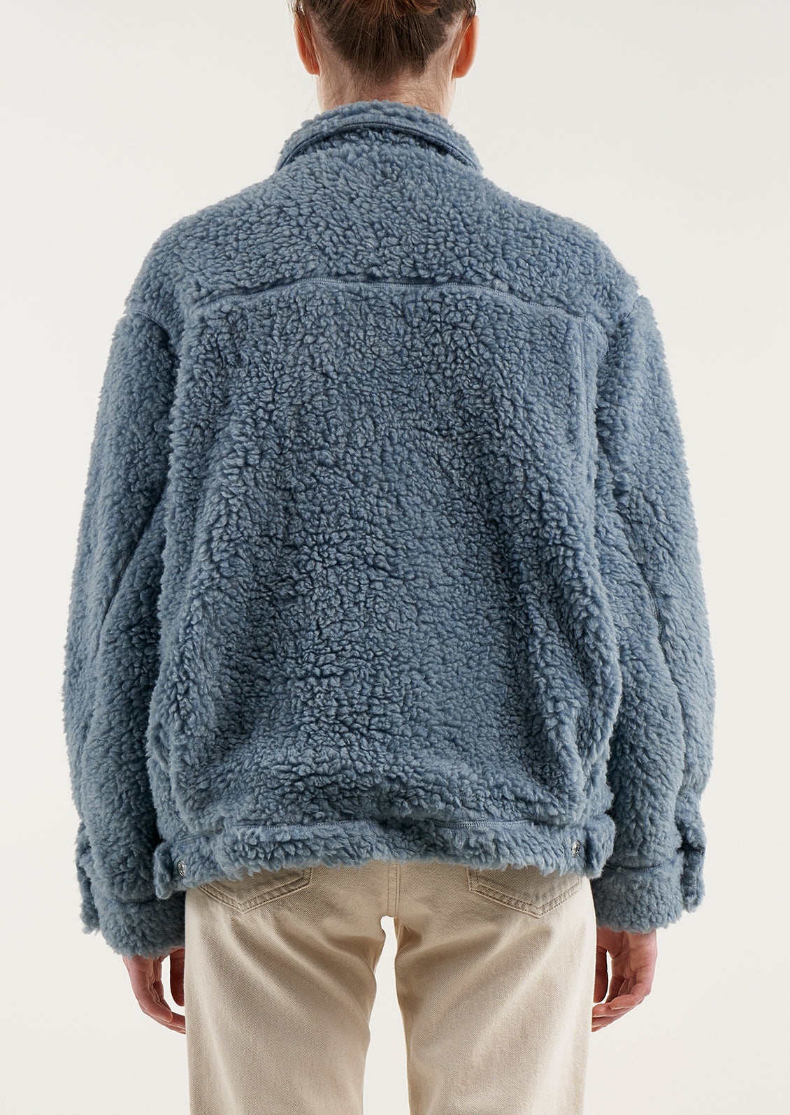 A woman wearing an oversized short jacket in dusty blue fleece.