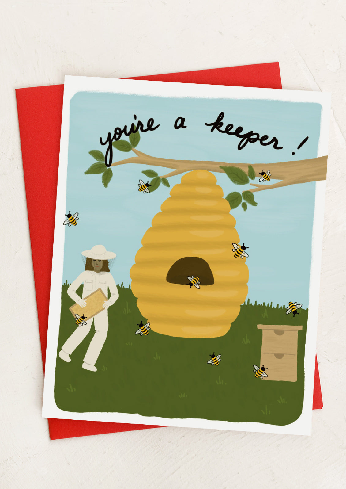 Greeting card with a beekeeper and beehive design, featuring the text 'you're a keeper!'.
