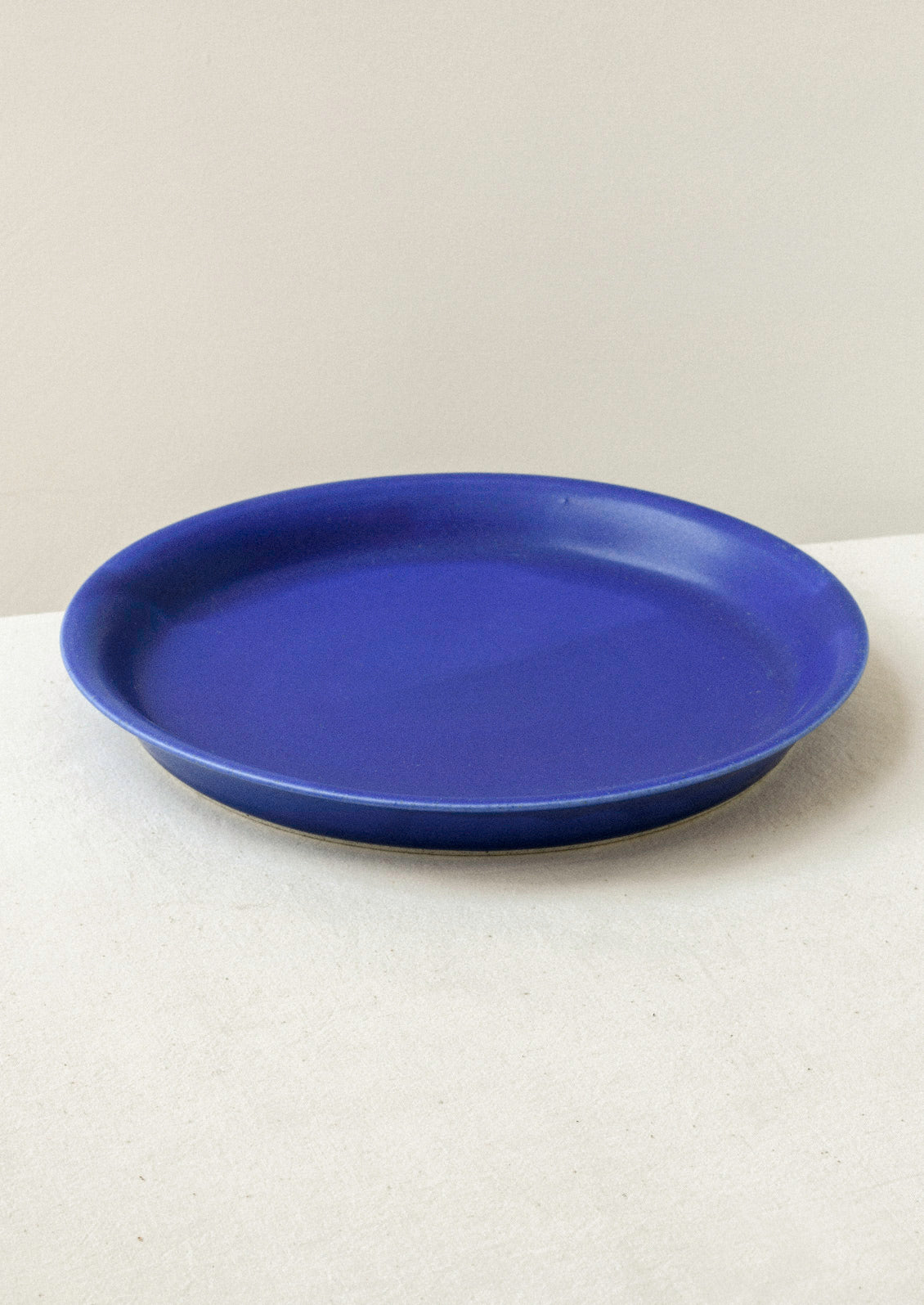 A large ceramic dinner plate in cobalt blue on a cream background.