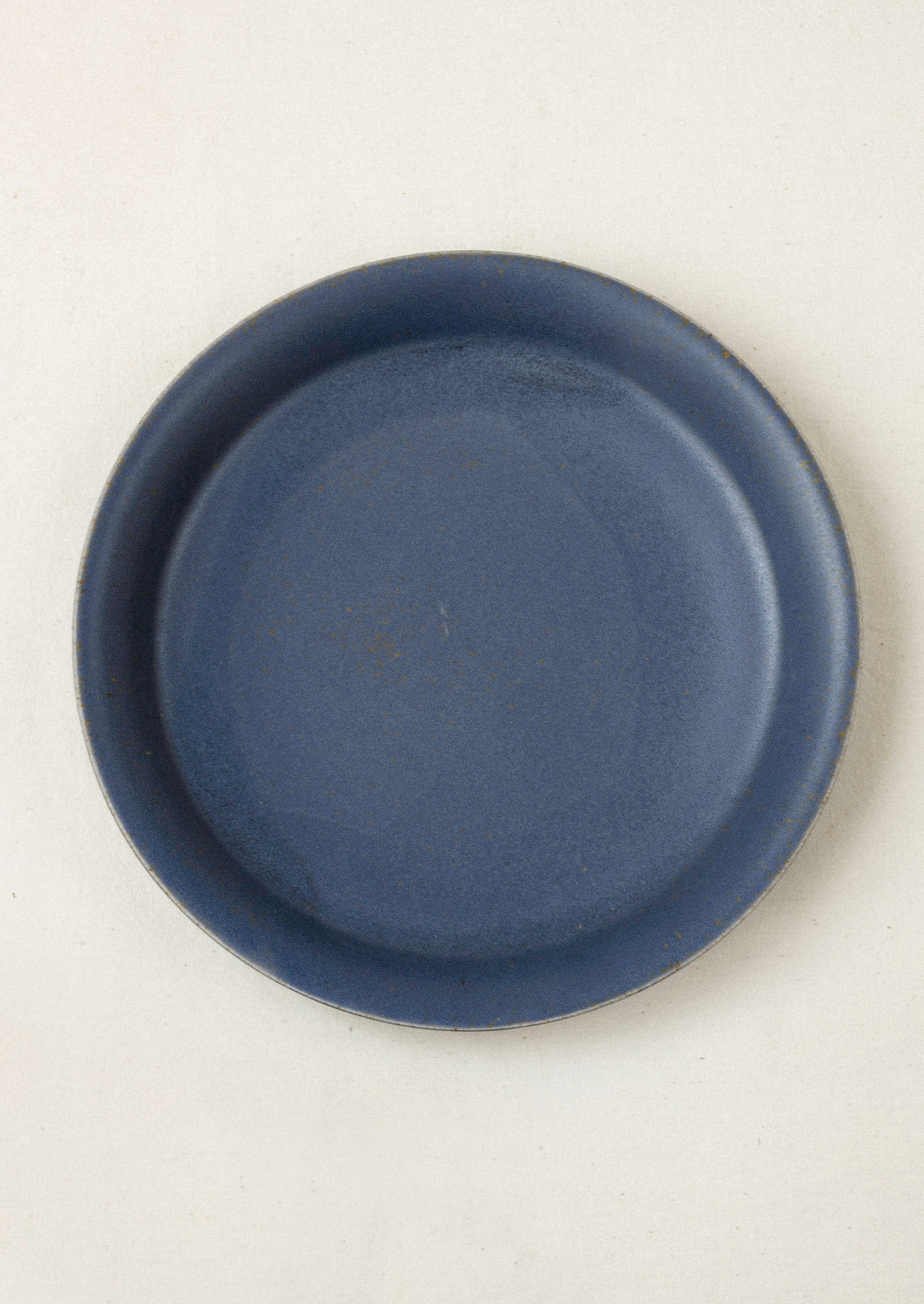 A large ceramic dinner plate in a charcoal color on a cream background.