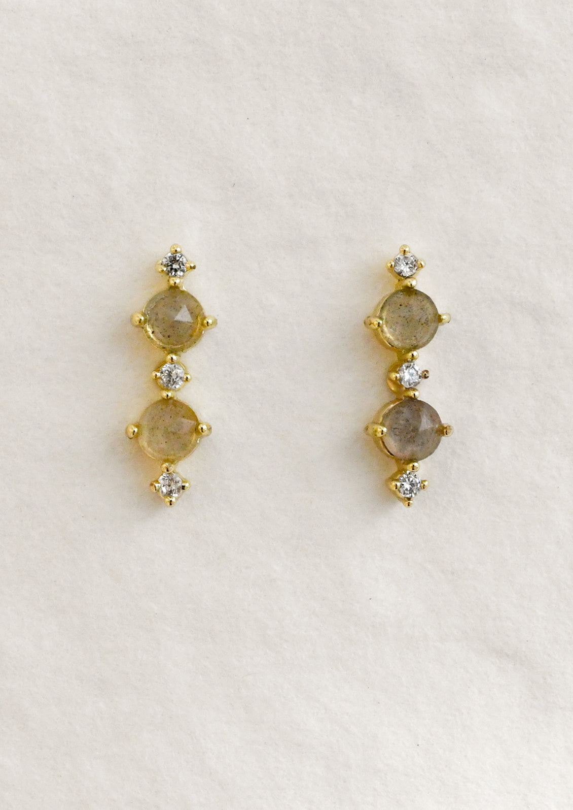 A pair of stud earrings with two labradorite stones between smaller cubic zirconia stones.