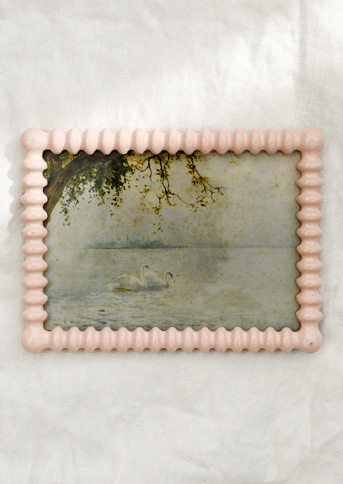A picture frame with barbed hobnail shape in high gloss baby pink lacquer.