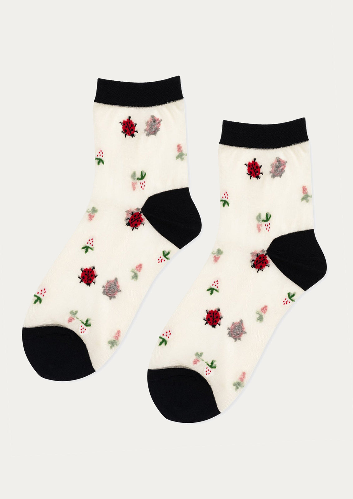 A pair of sheer white socks with ladybug and berry pattern, and black trim.