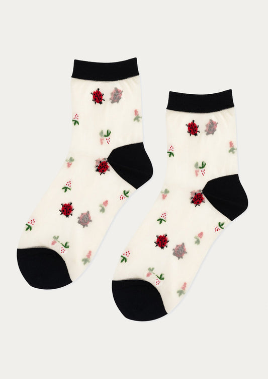 A pair of sheer white socks with ladybug and berry pattern, and black trim.
