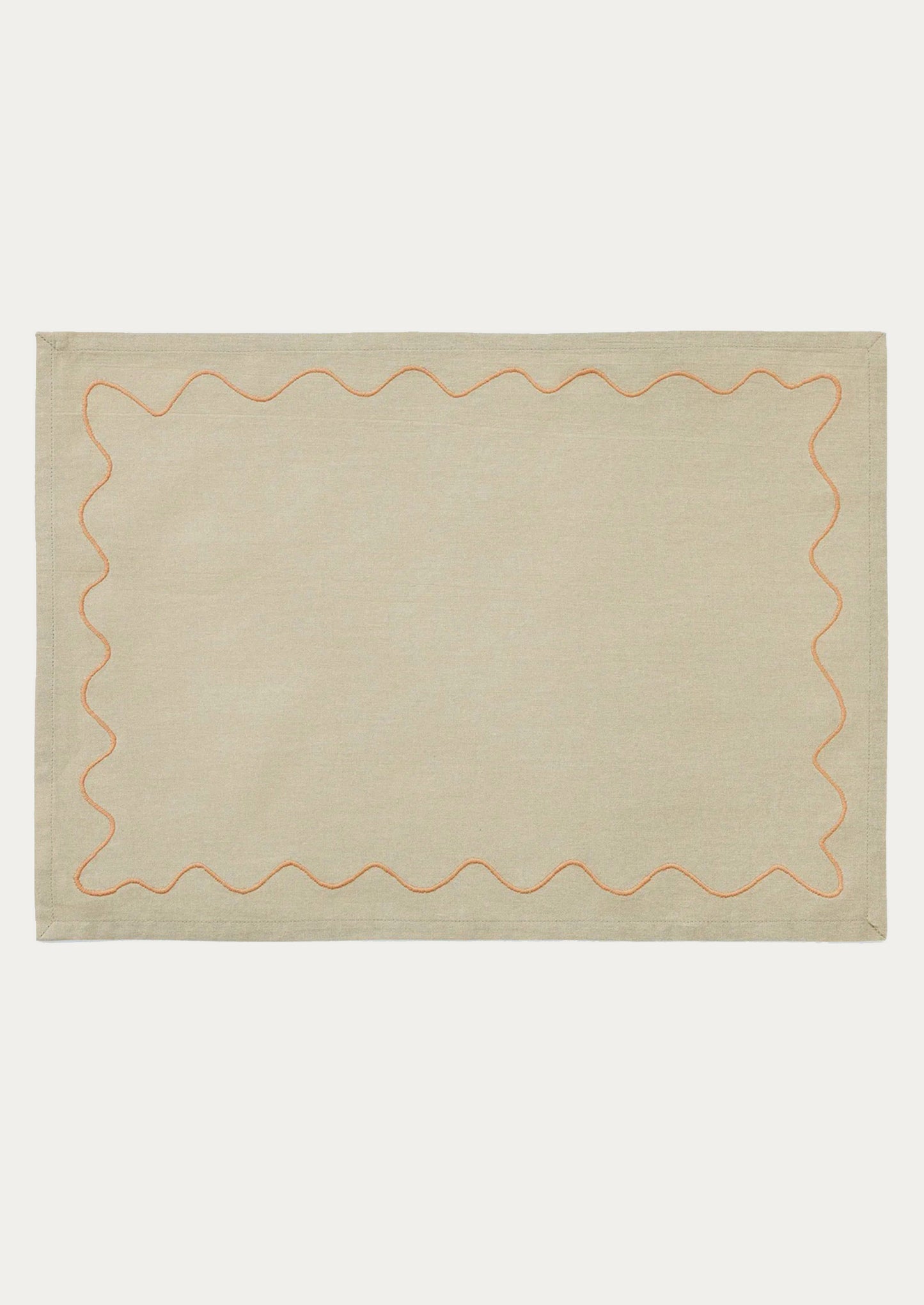 A tan placemat with peach squiggle border.