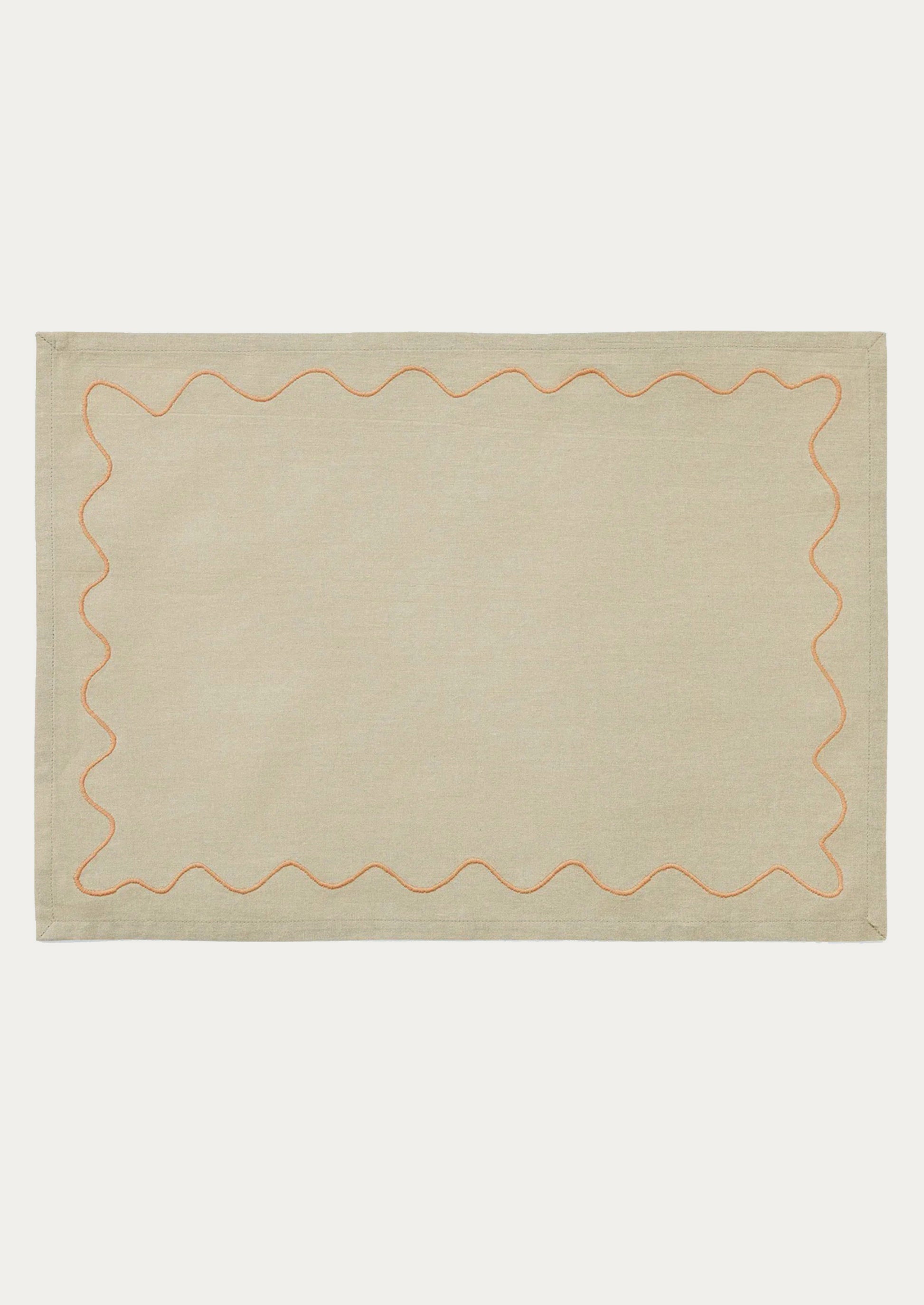 A tan placemat with peach squiggle border.