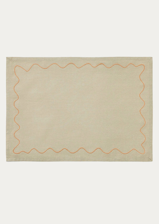 A tan placemat with peach squiggle border.