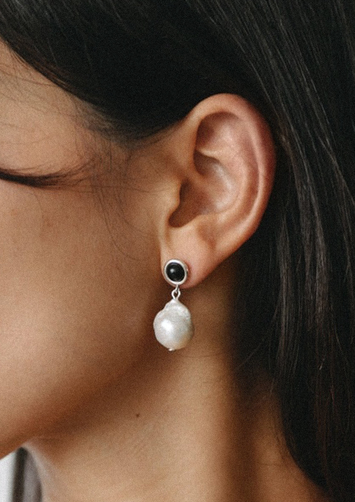 A pair of sterling slver earrings with a black gem and a large pearl.
