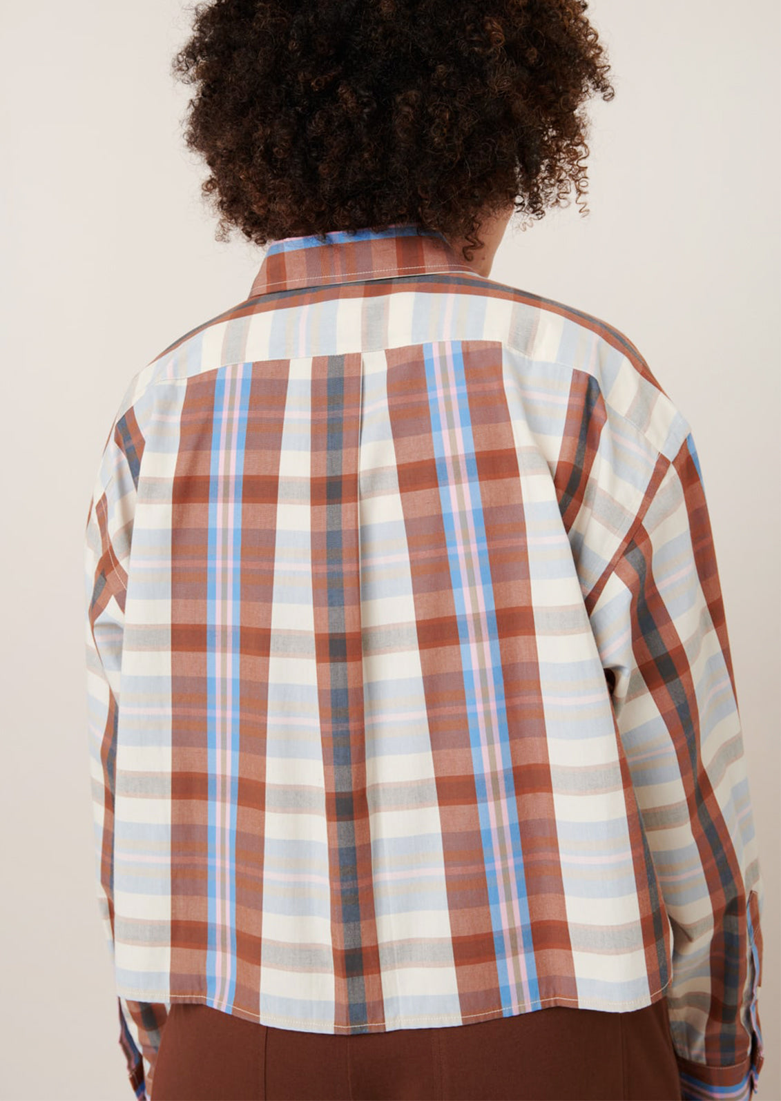 A woman wearing a multicolor plaid cropped shirt.
