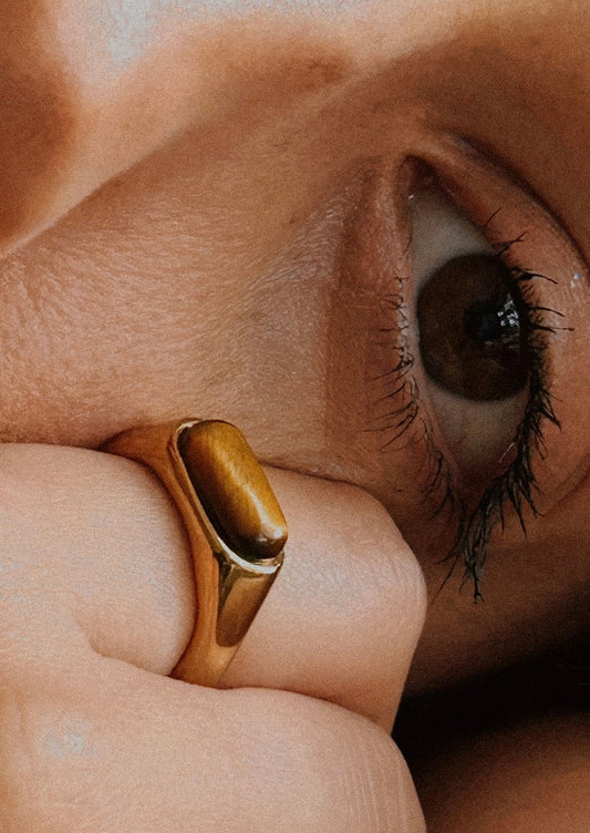 A gold ring with an marbled brown gemstone.