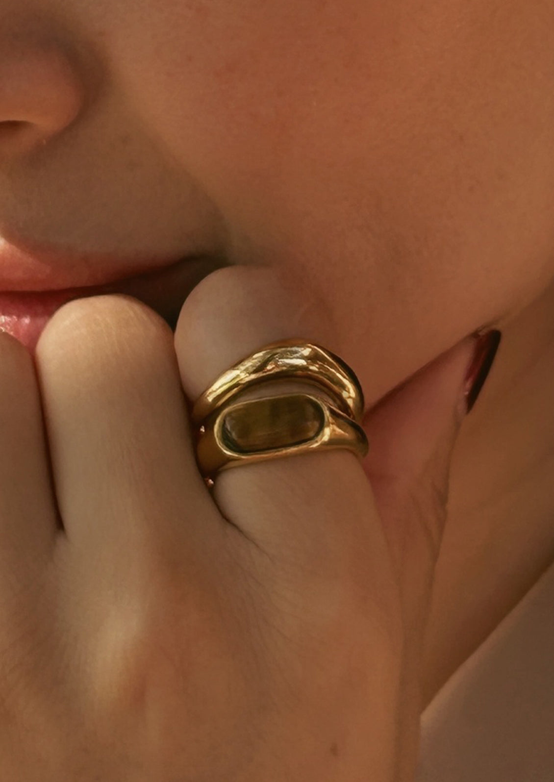 A gold ring with an marbled brown gemstone.