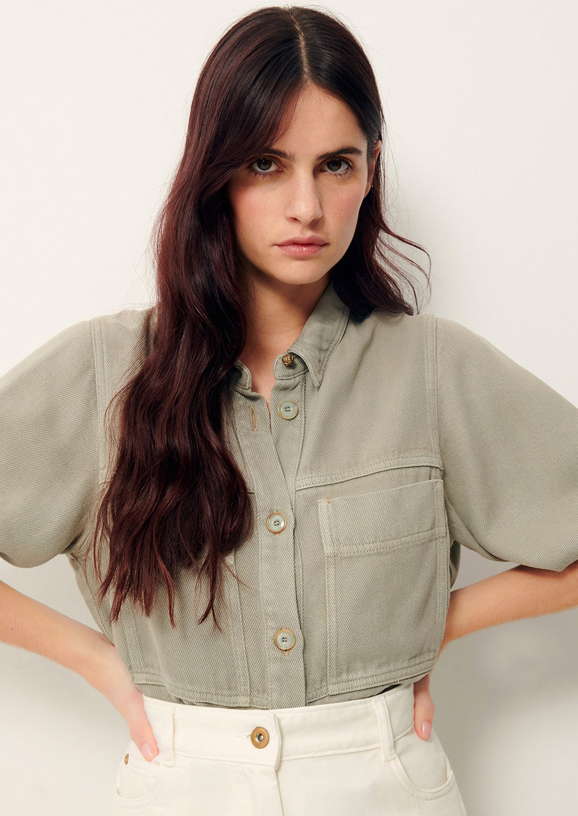 Woman wearing light gray denim shirt jacket. 