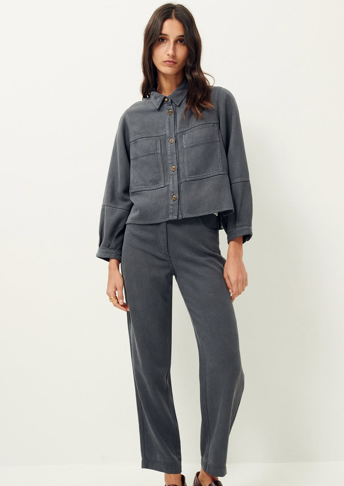 Woman wearing dark gray denim shirt jacket and gray pants. 