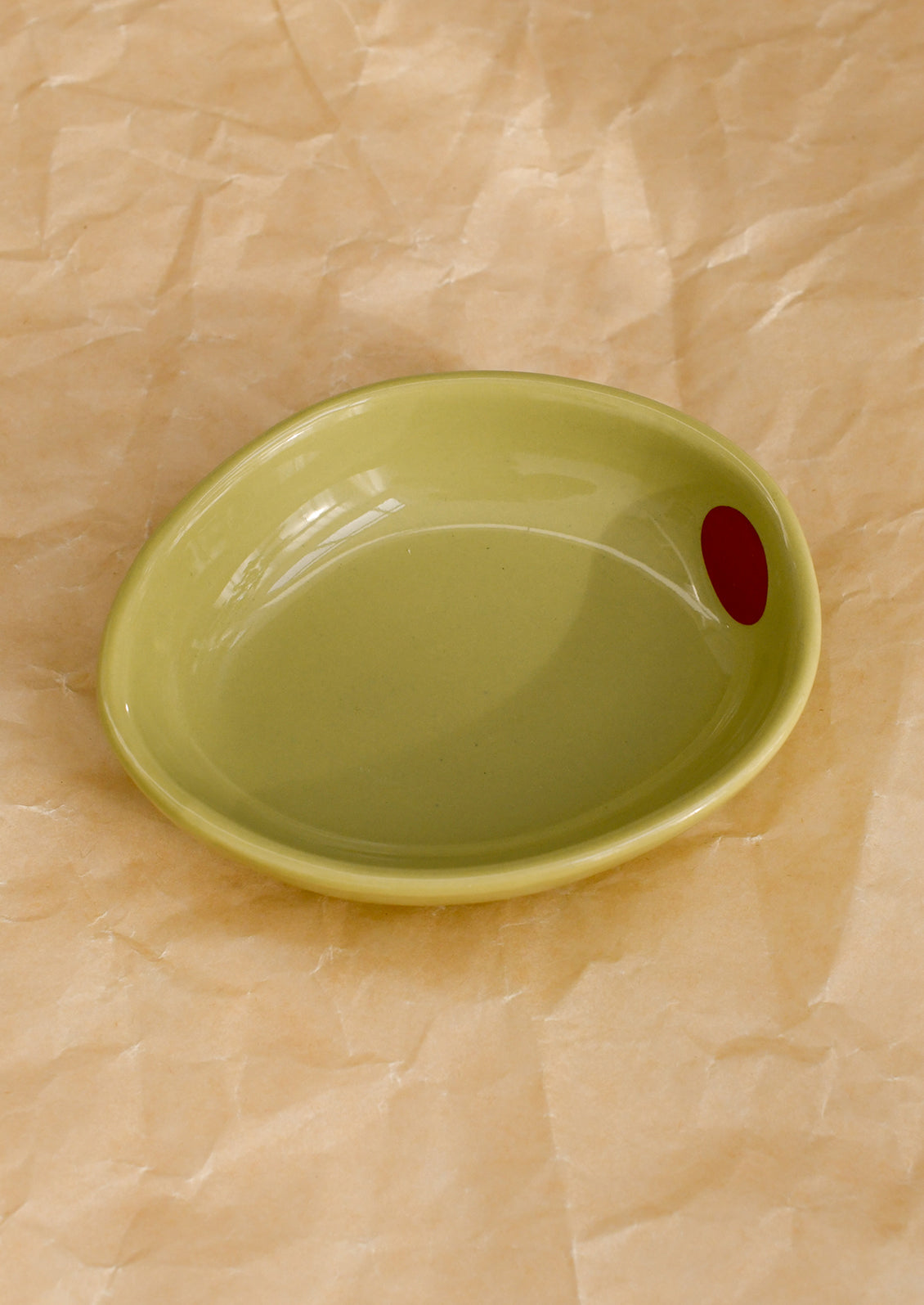 A small ceramic bowl shaped like an olive in light green.