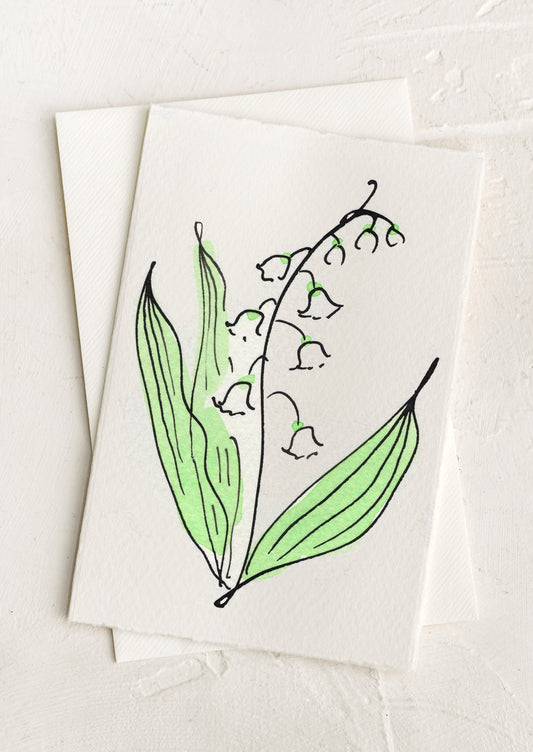 A blank greeting card with hand painted illustration of a lily of the valley flower.