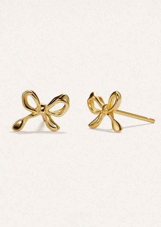 A pair of small stud earrings in gold, in the shape of a small bow.