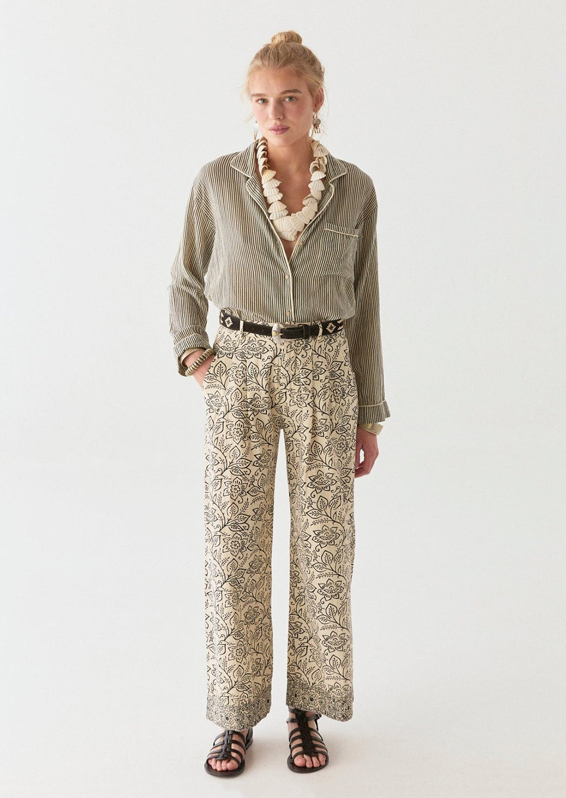 A woman wearing a pair of cream pants with black floral print.