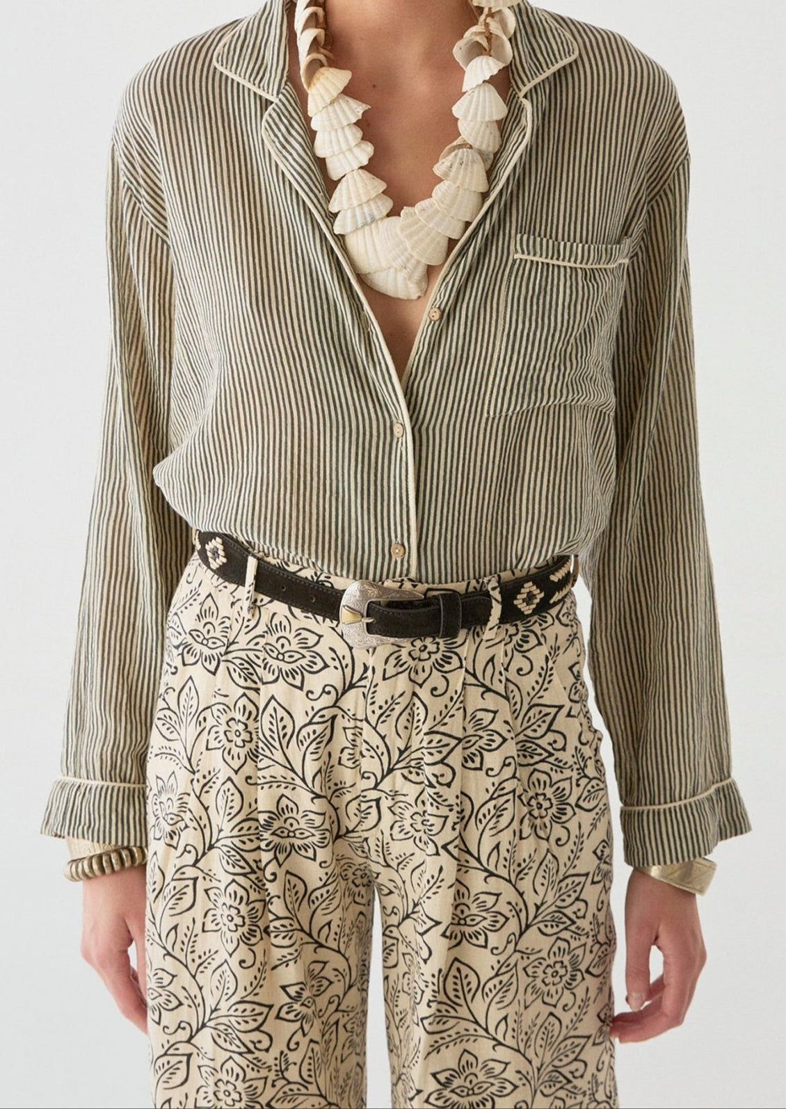 A woman wearing a pair of cream pants with black floral print.