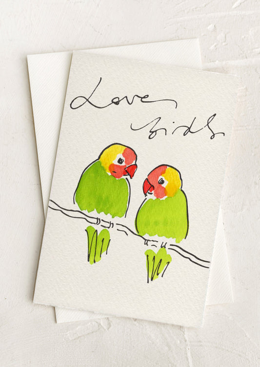 Greeting card with illustration of two green birds on a branch and 'Love Birds' text.