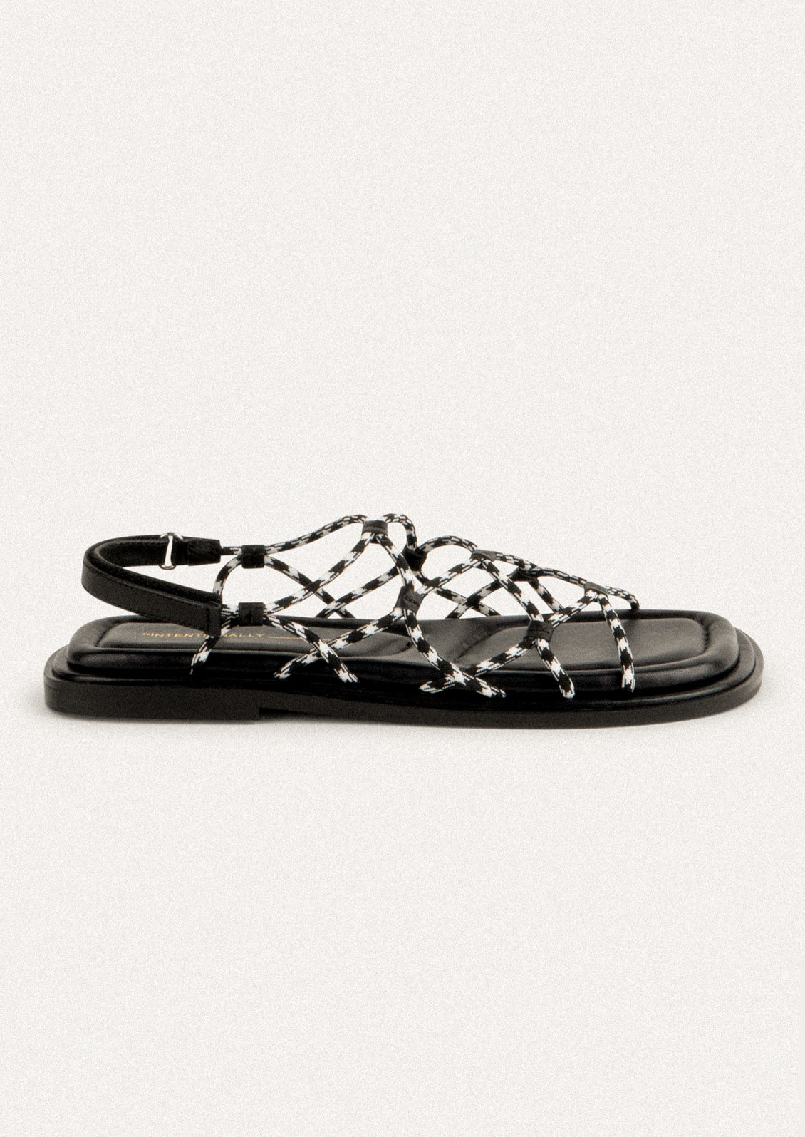 A pair of flat sandals with black and white paracord upper.