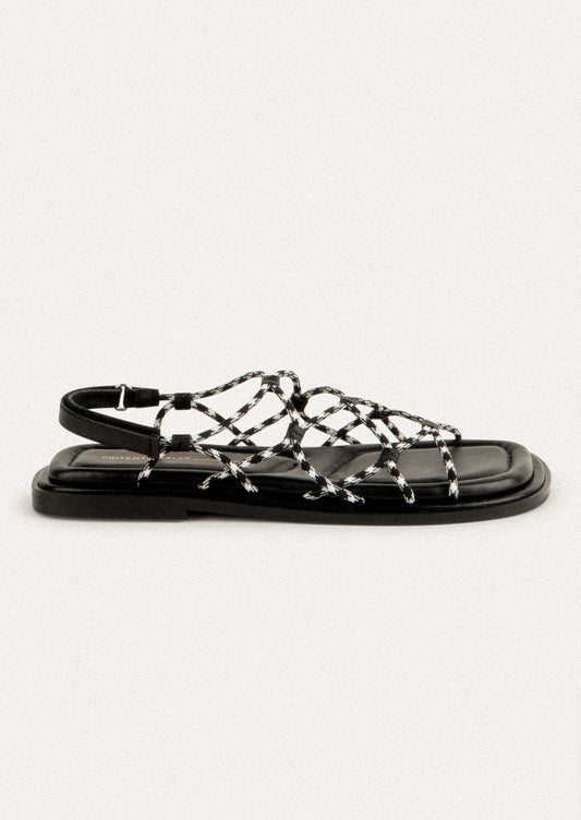 A pair of flat sandals with black and white paracord upper.