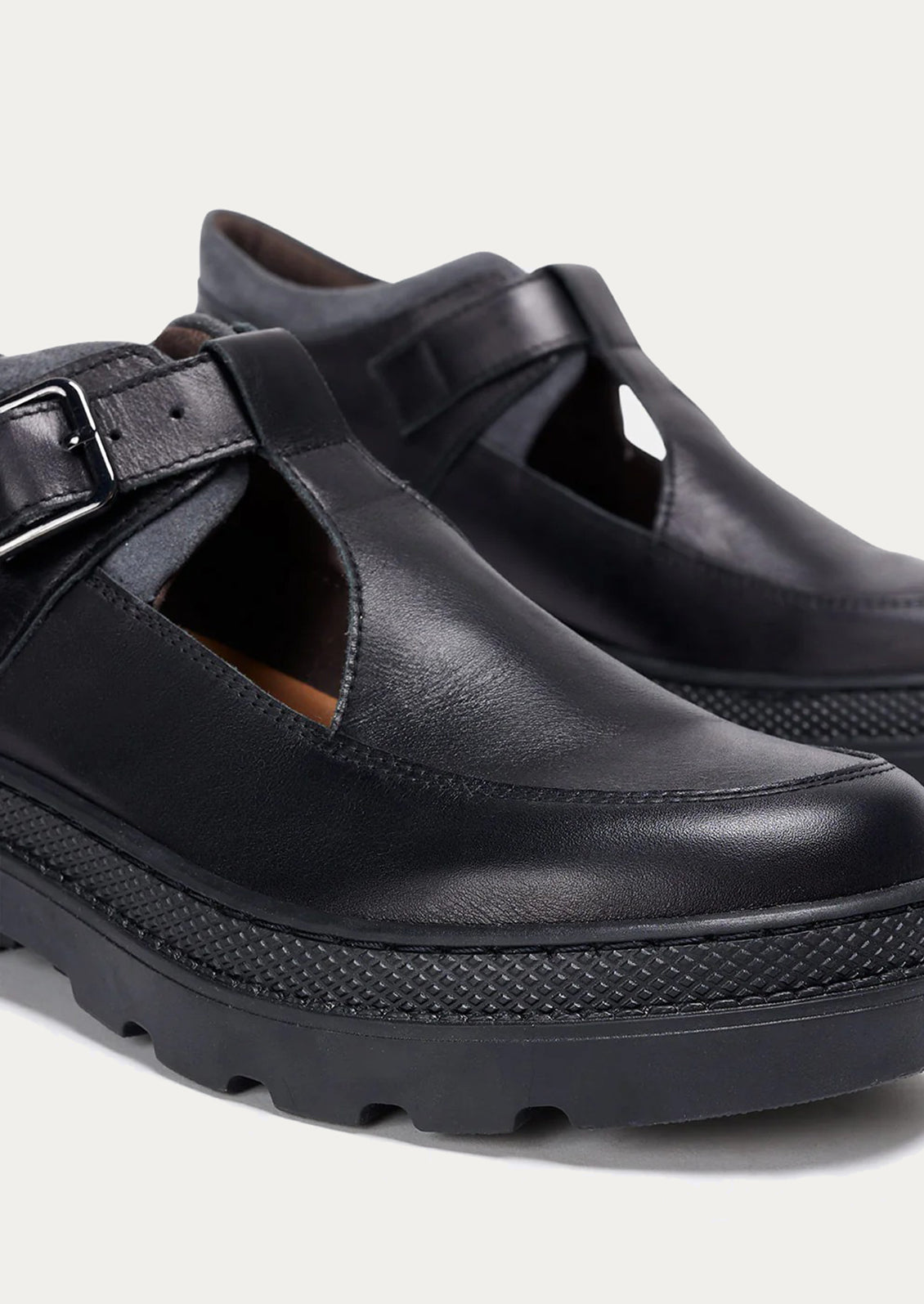 Black leather shoes with a strap on a light gray background