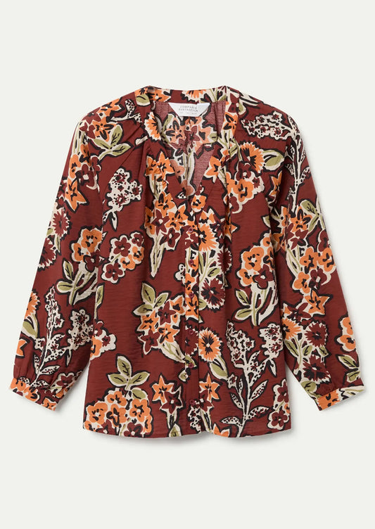 A floral print long sleeve blouse in rust with orange floral pattern.