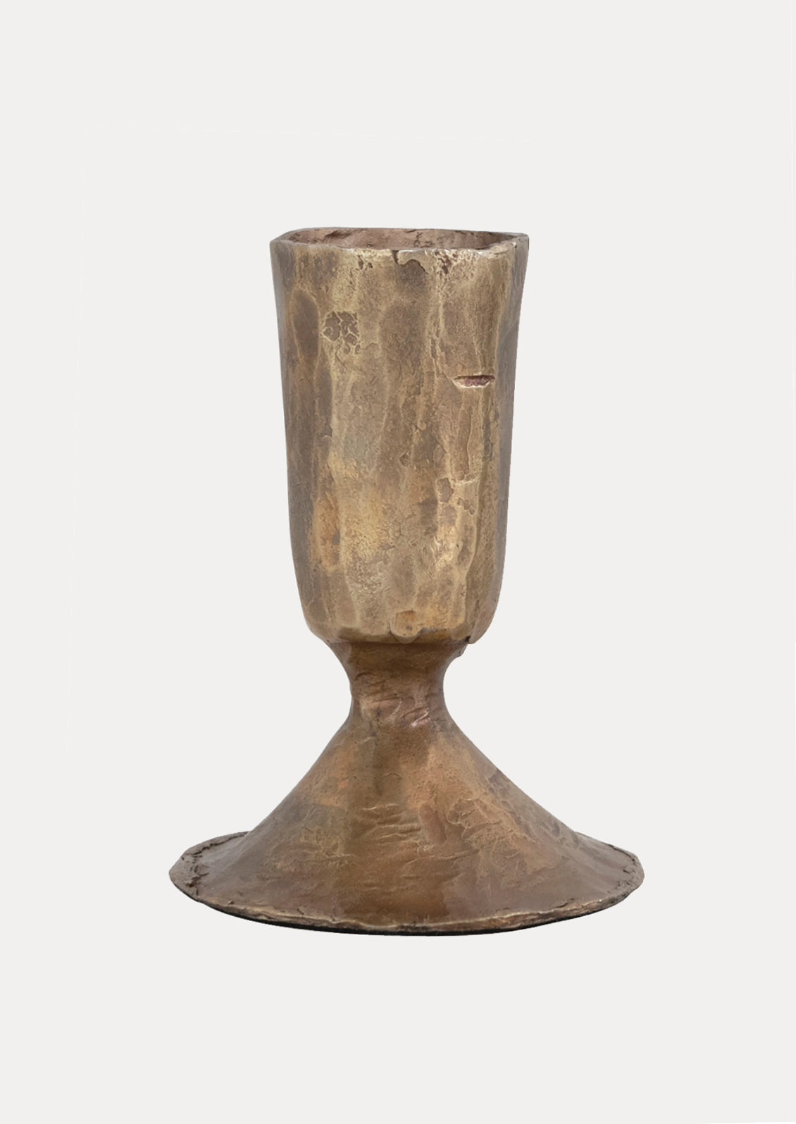 A brass toned metal candlestick holders with a carved texture and tapered shape.
