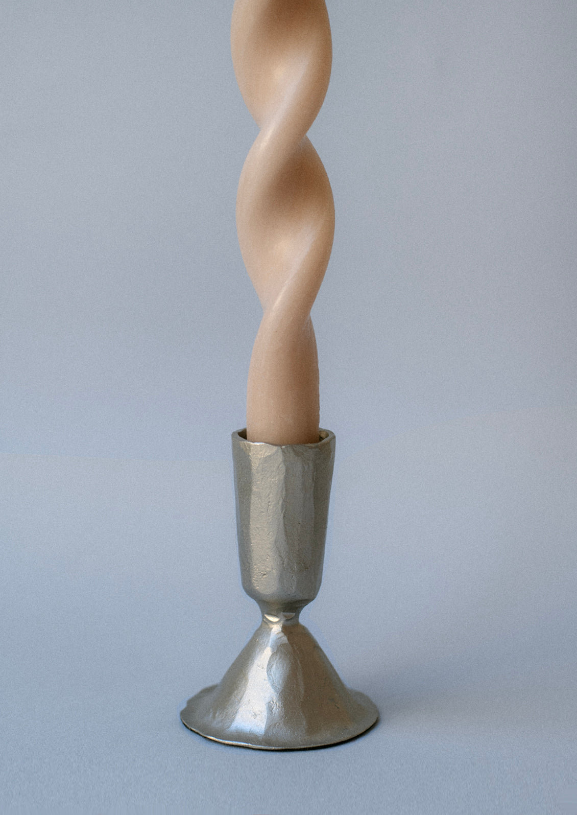 A silver metal candlestick holders with a carved texture and tapered shape.