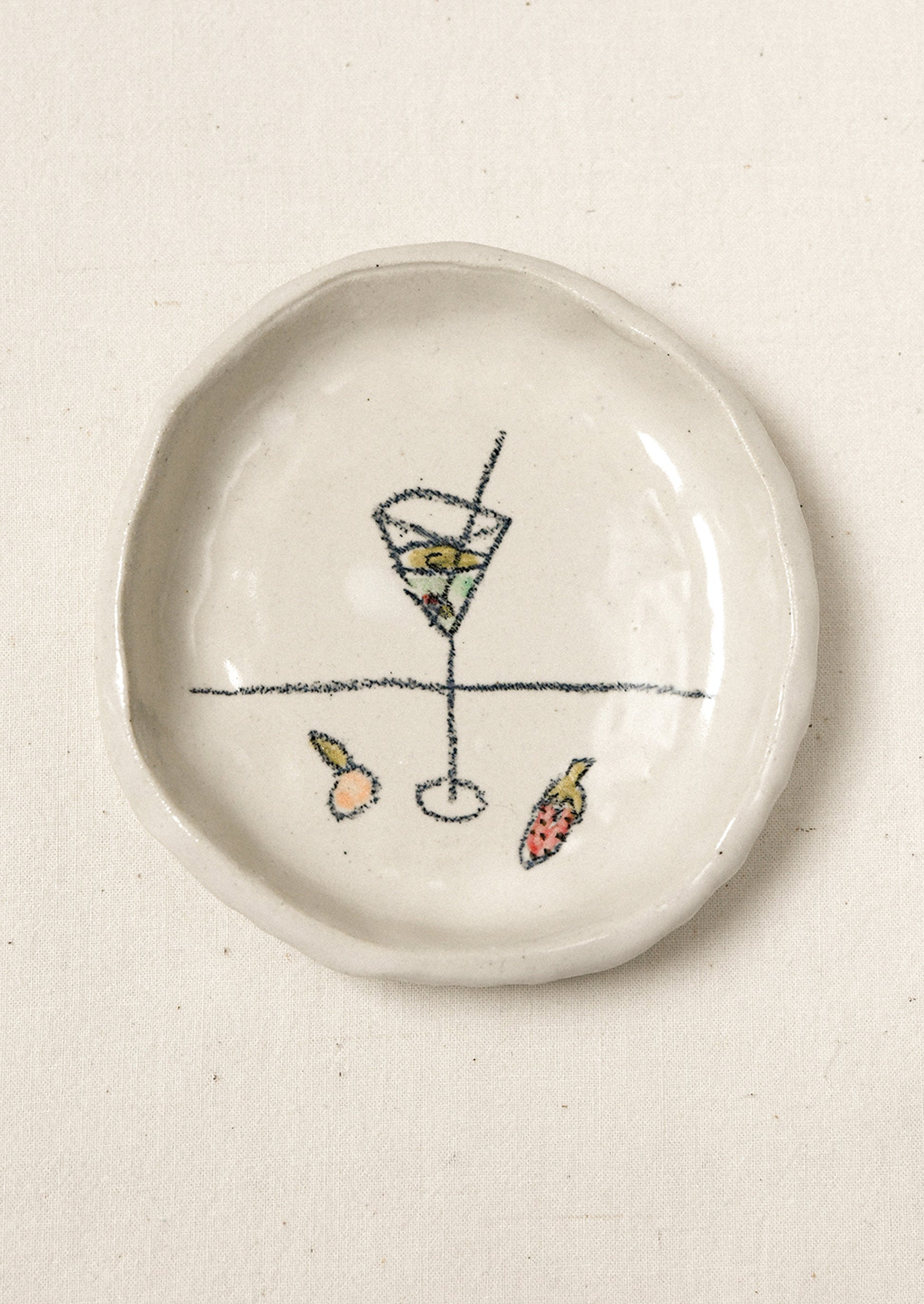 A small ceramic dish with an illustration of a martini glass and fruits.