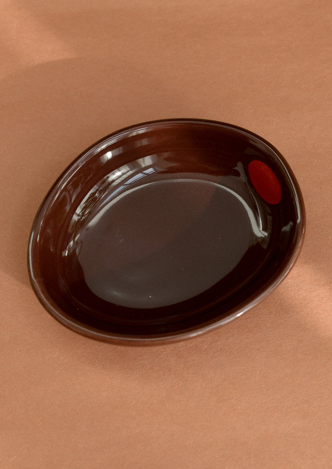 A small ceramic bowl shaped like an olive in burgundy.