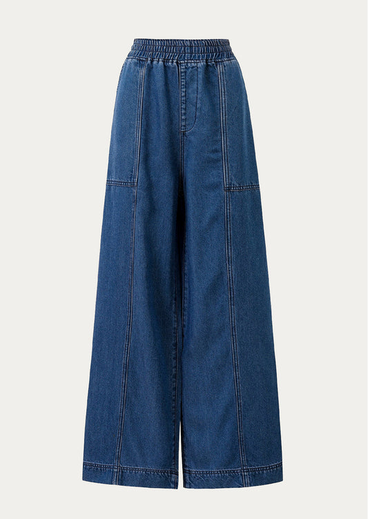 A person wearing a pair of relaxed denim pants with elasticized waistband.