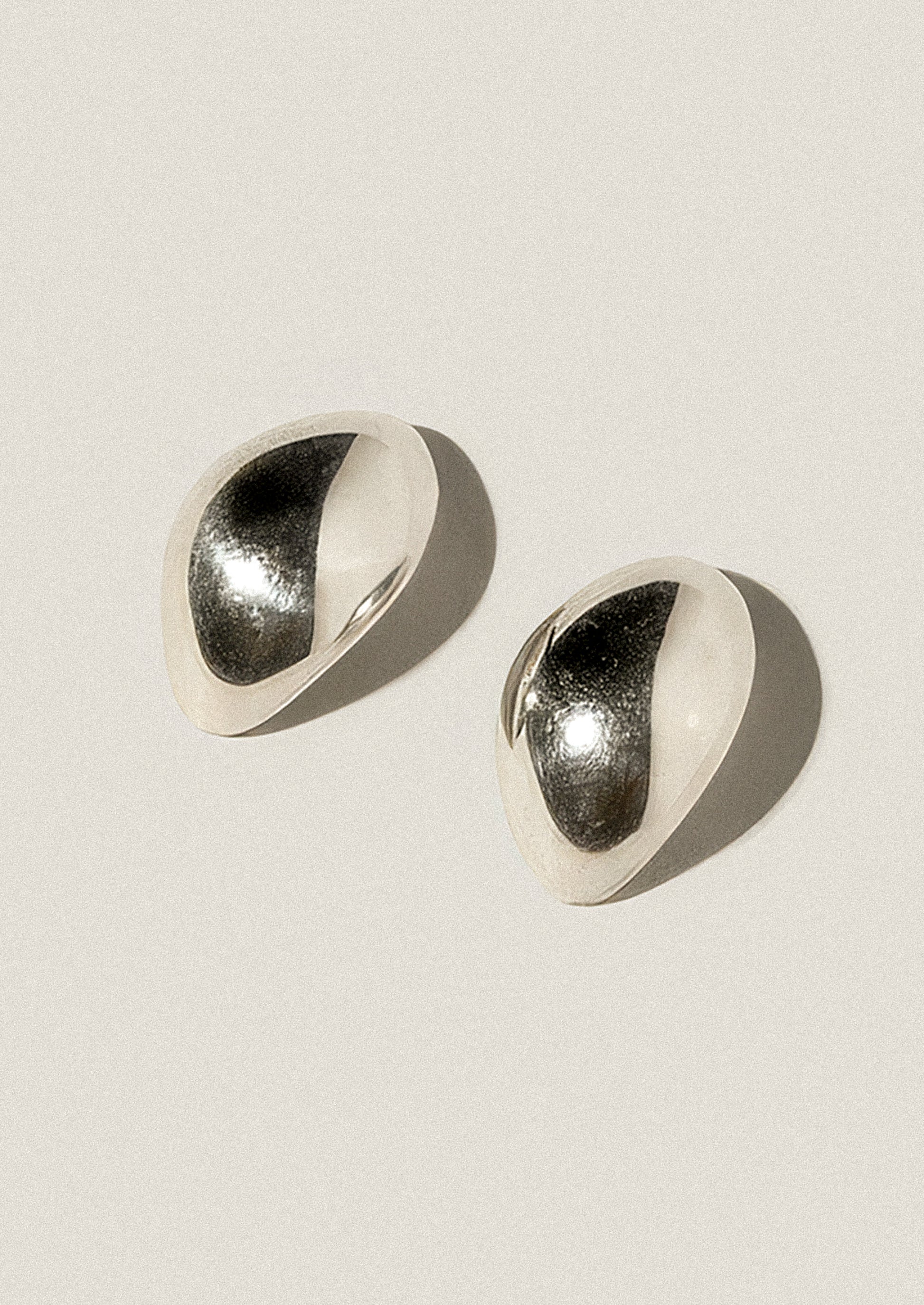 Pair of silver earrings on a light beige background