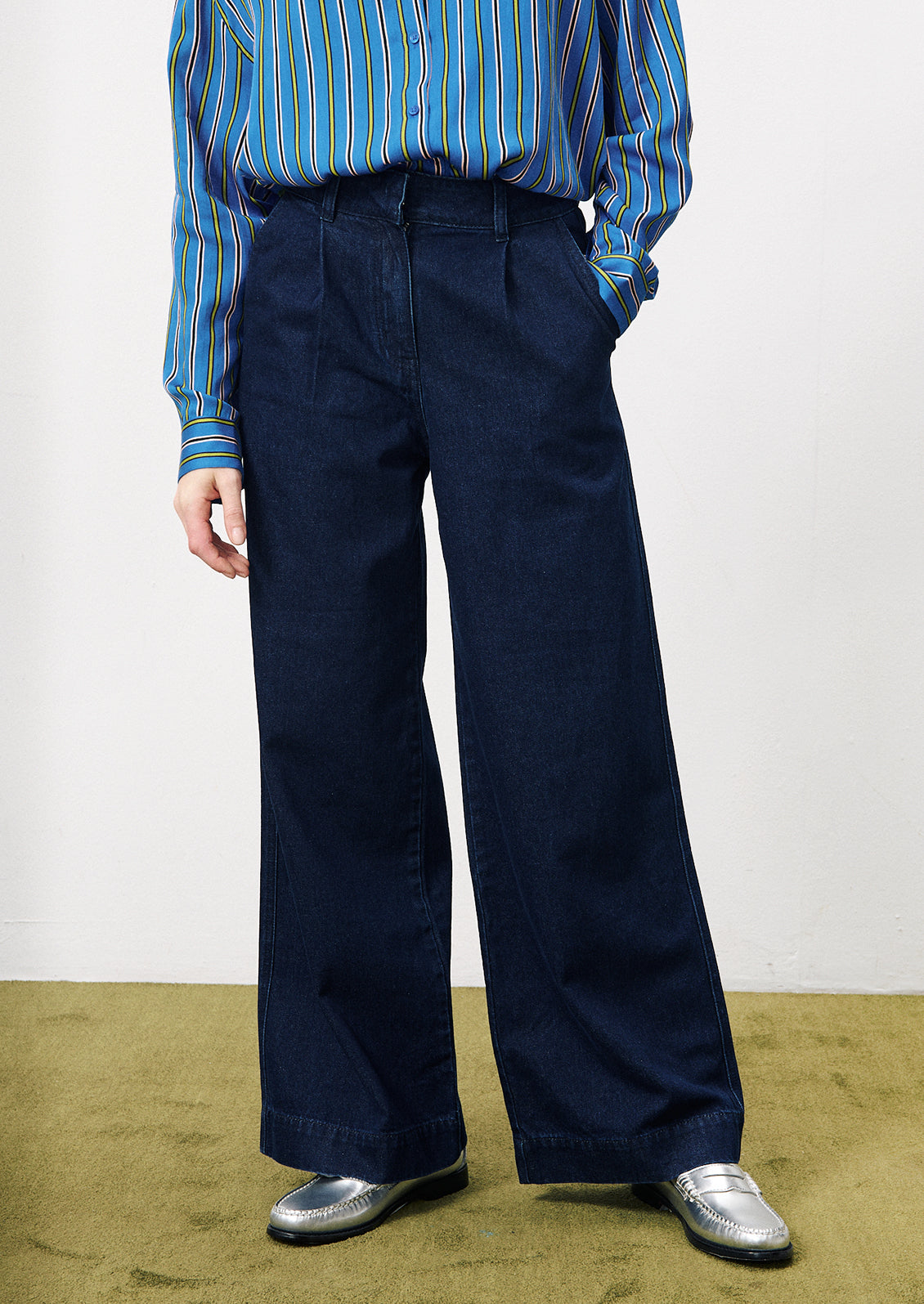 A woman wearing a pair of wide leg trouser style jeans in dark inky denim.