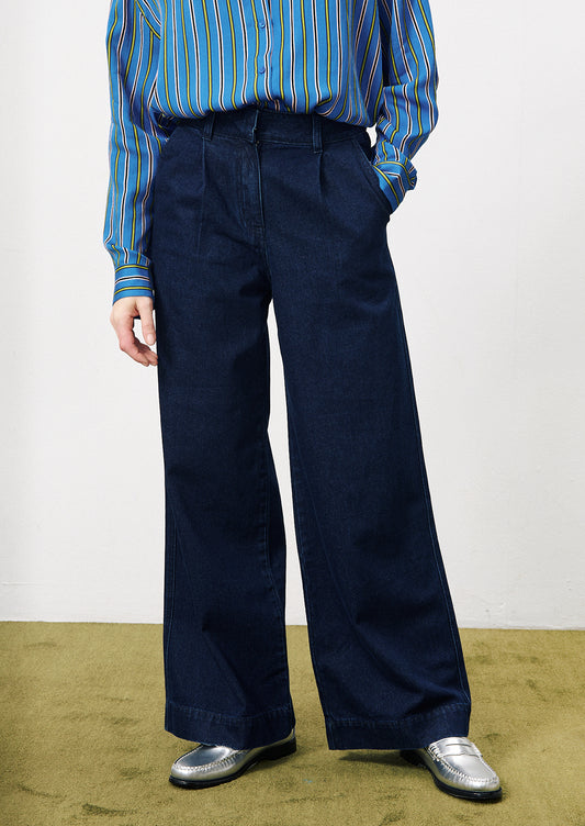 A woman wearing a pair of wide leg trouser style jeans in dark inky denim.