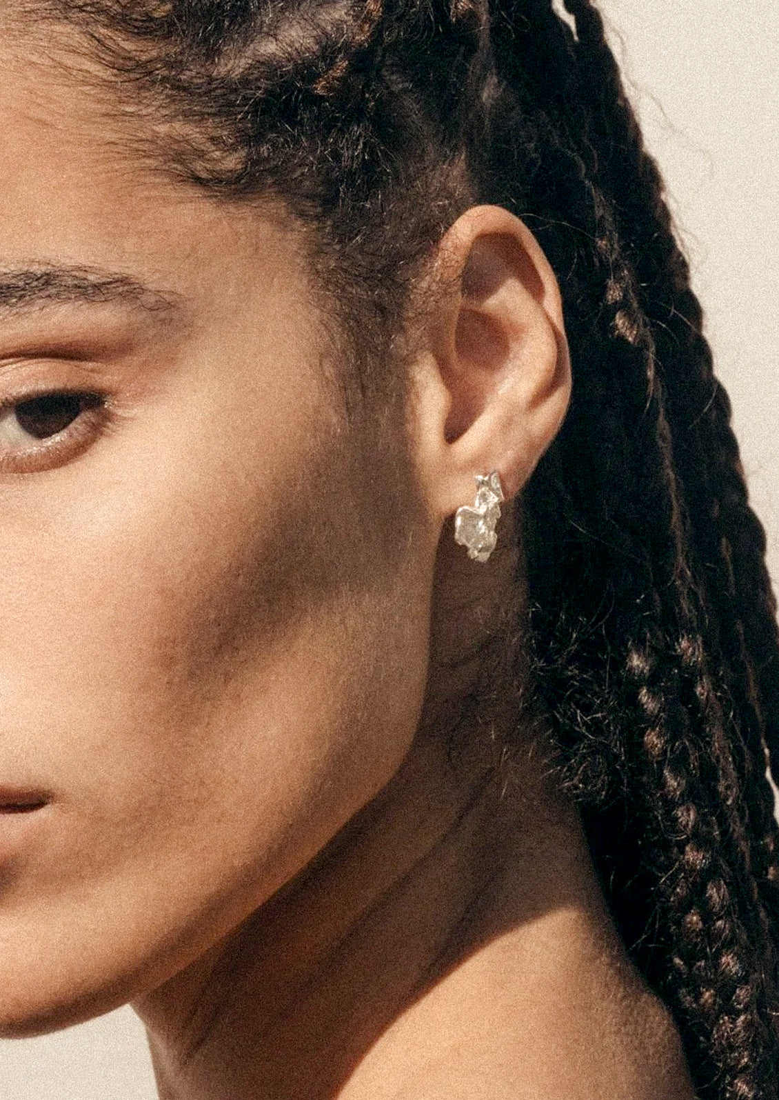 A woman wearing a sterling silver teardrop earring in an abstract shape.