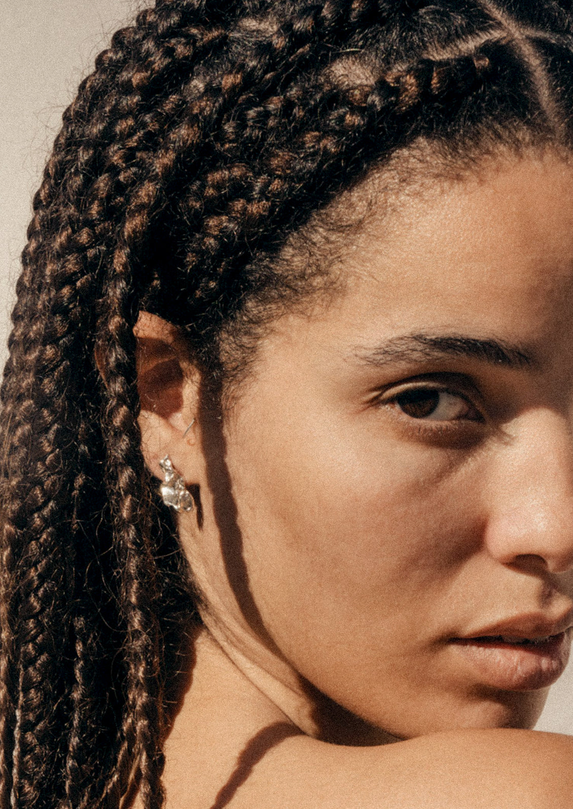 A woman wearing a sterling silver teardrop earring in an abstract shape.