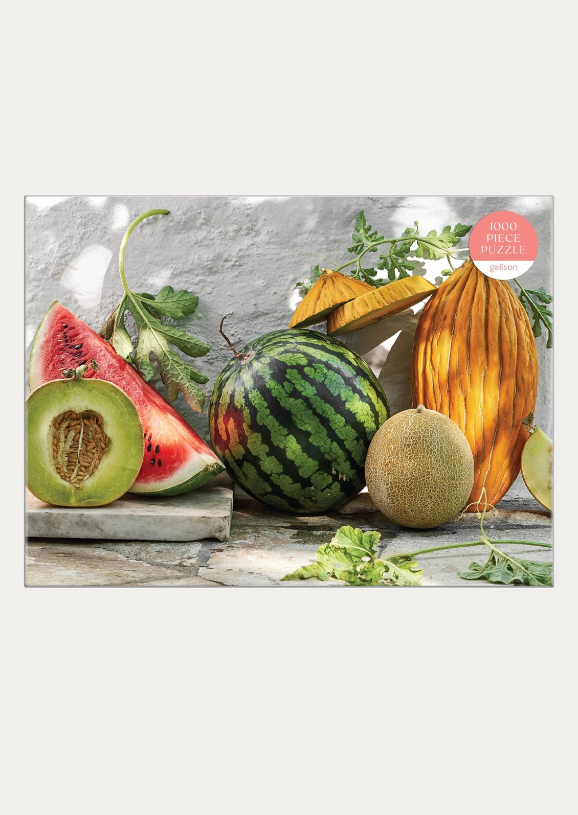 A 1000-piece fruit and vegetable still life jigsaw puzzle, featuring watermelons, cantaloupe, honeydew, and herbs on a rustic stone surface against a textured gray wall. 