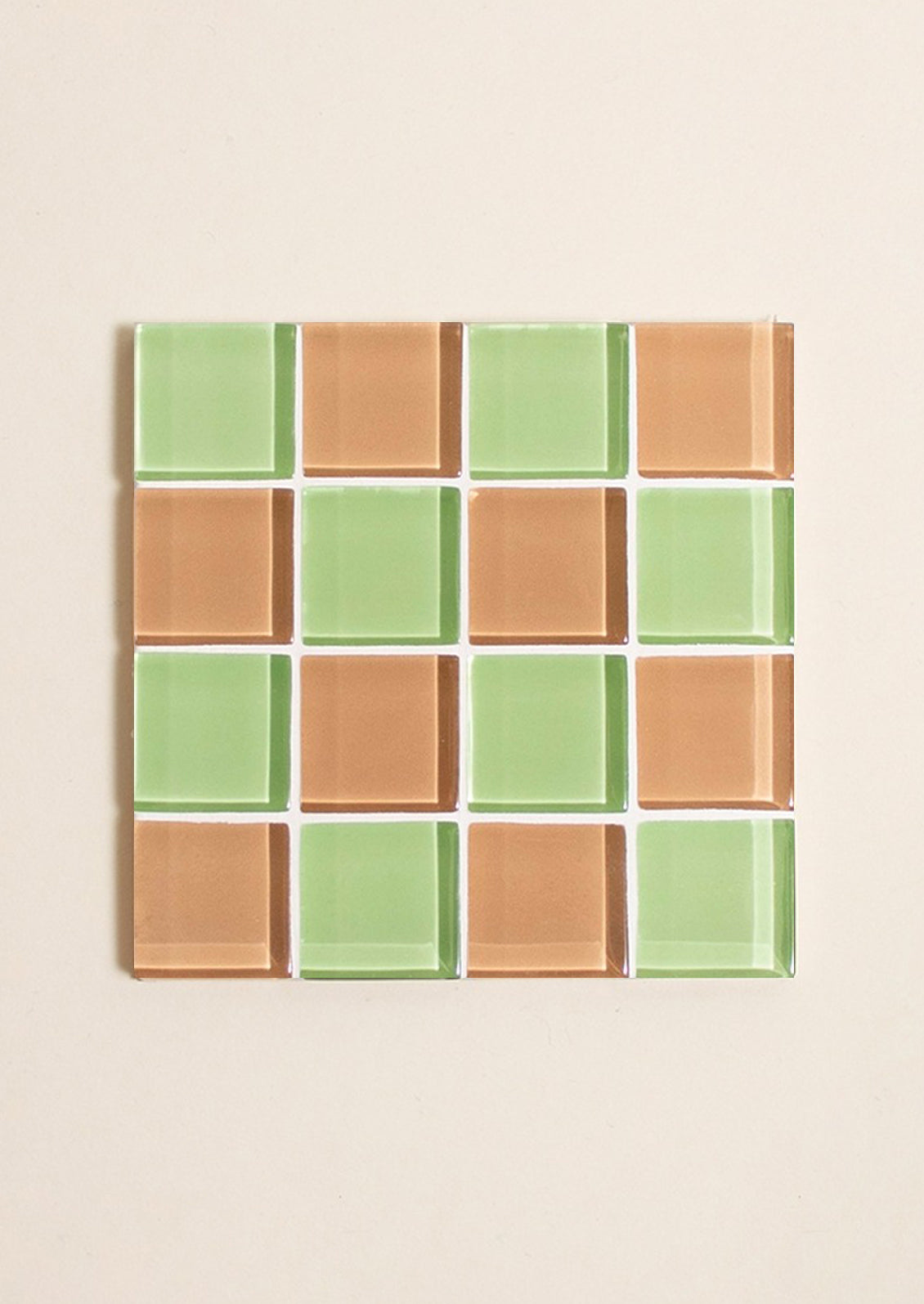 A glass tile coaster in two tone checker pattern in mint green and chocolate brown.