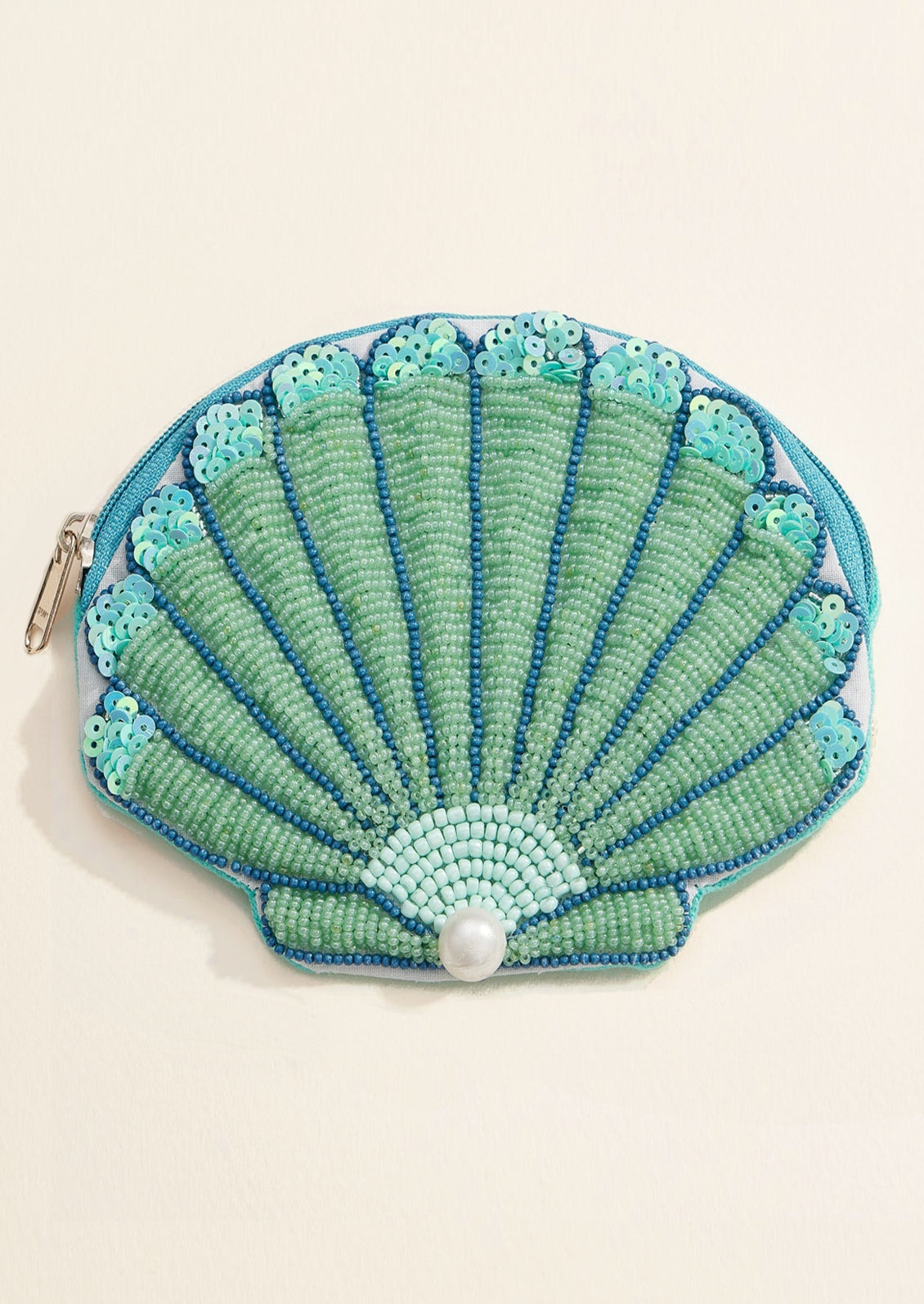 Shell-shaped beaded purse with a pearl on a beige background