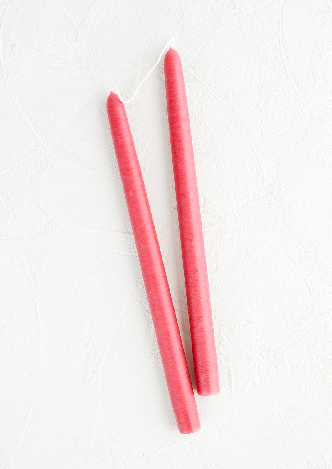 A pair of taper candles in raspberry pink.
