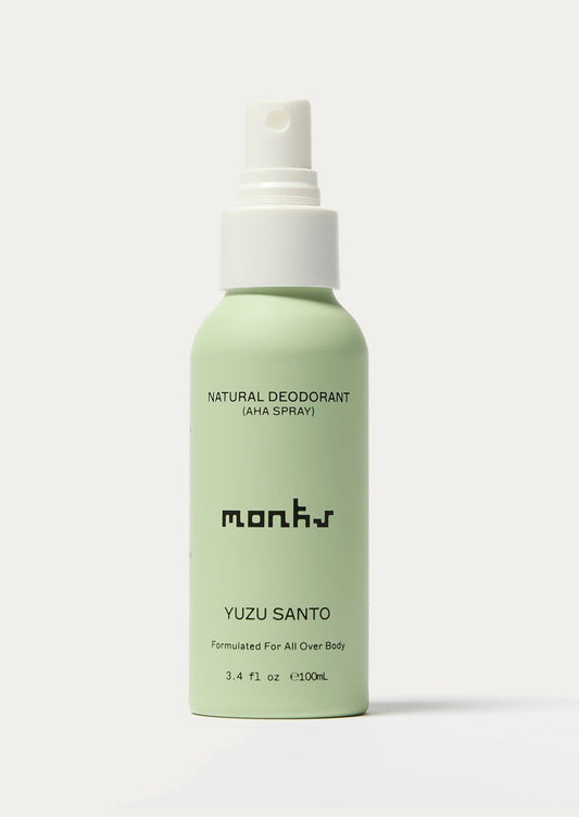 Green deodorant spray bottle with white cap on a light gray background