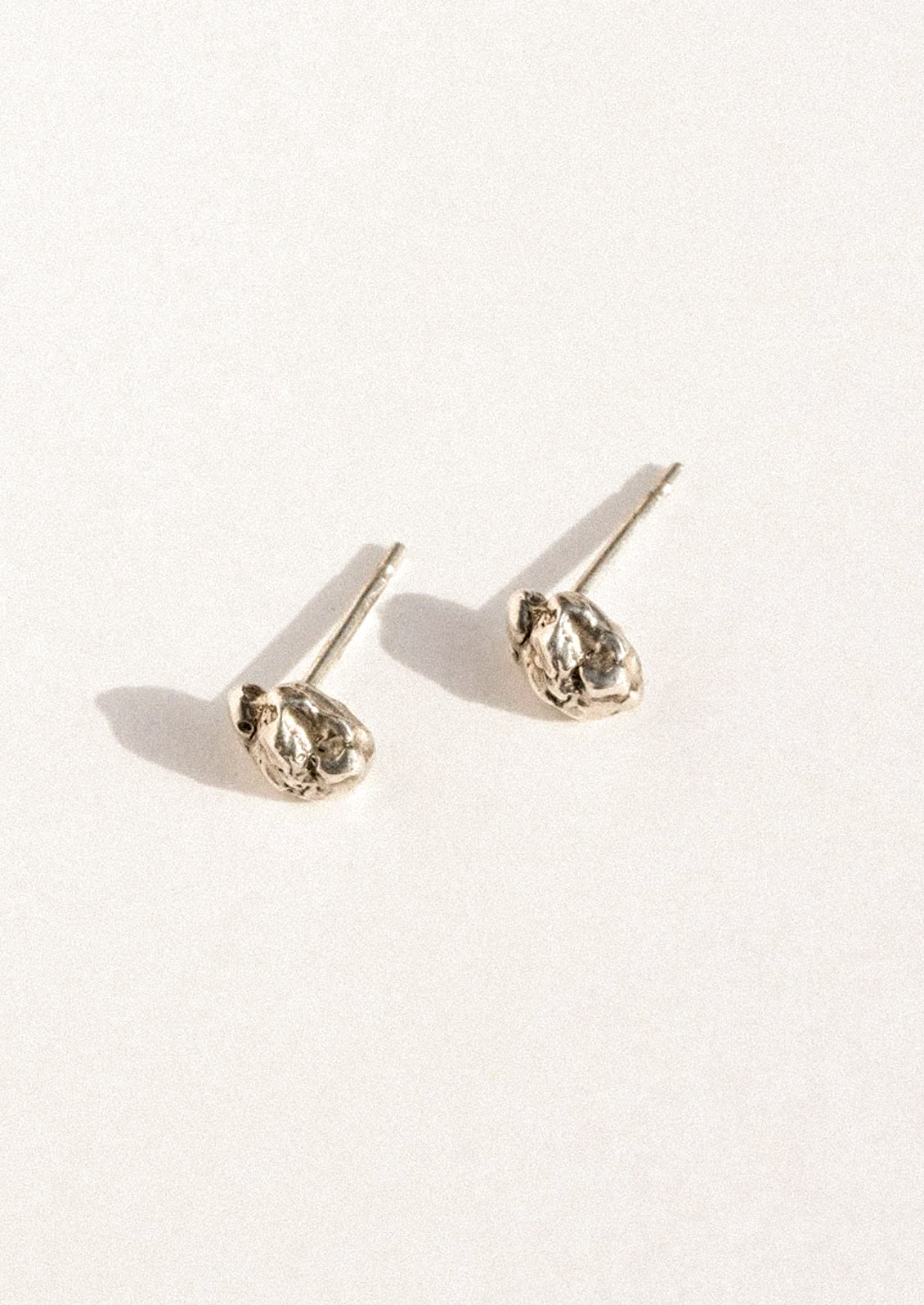 A pair of sterling silver stud earrings in an abstract shape.
