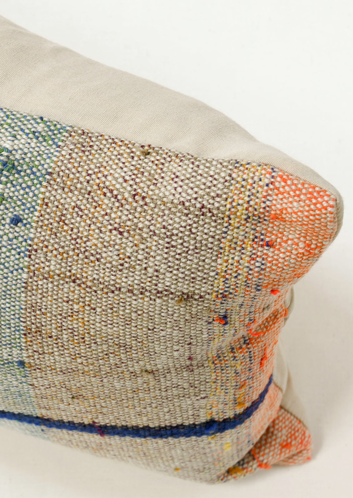 Closeup of a rectangular 12" x 24" mottled kilim pillow with various colored striped throughout.