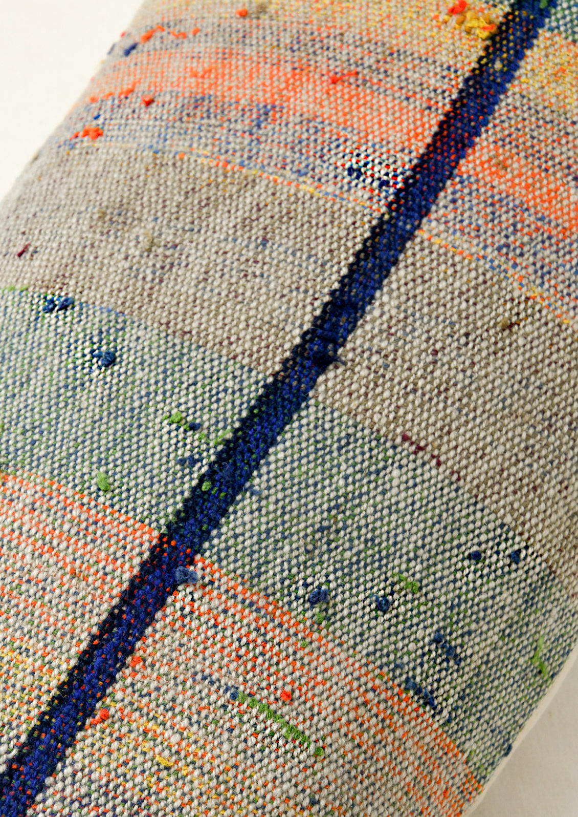 Closeup of a rectangular 12" x 24" mottled kilim pillow with various colored striped throughout.