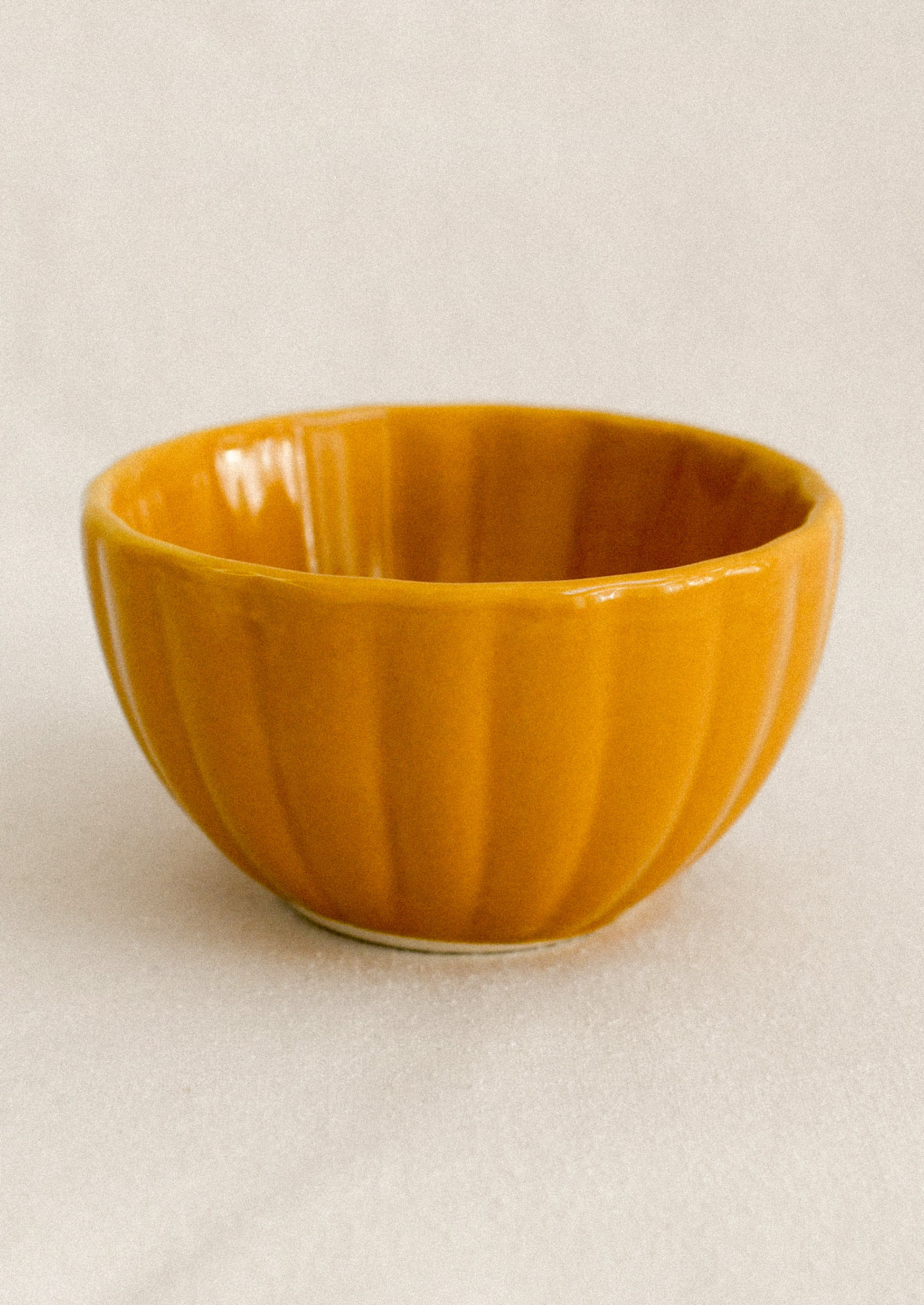 Mustard ceramic bowl on a beige background