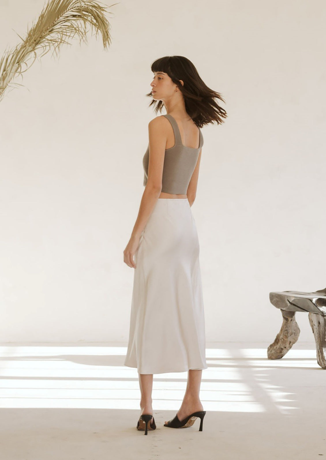 A woman wearing a form fitting square neck tank top in greige color.