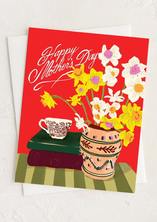 Greeting card with flowers, teacup, and books on a red background