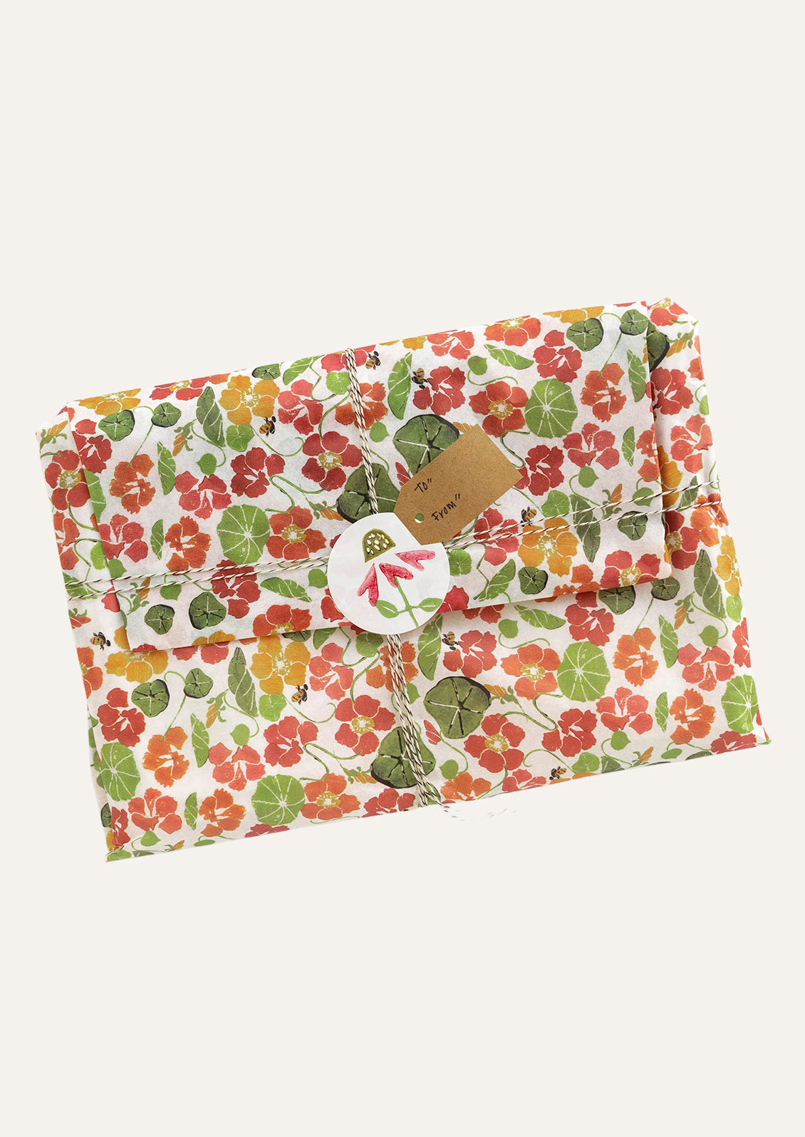 A gift wrapped in tissue paper featuring a red and orange nasturtium flower pattern.